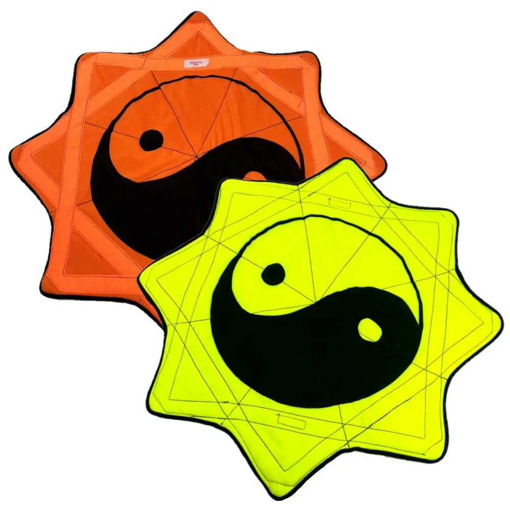 Neon yellow and orange kite with black yin yang symbol on a geometric pattern background.